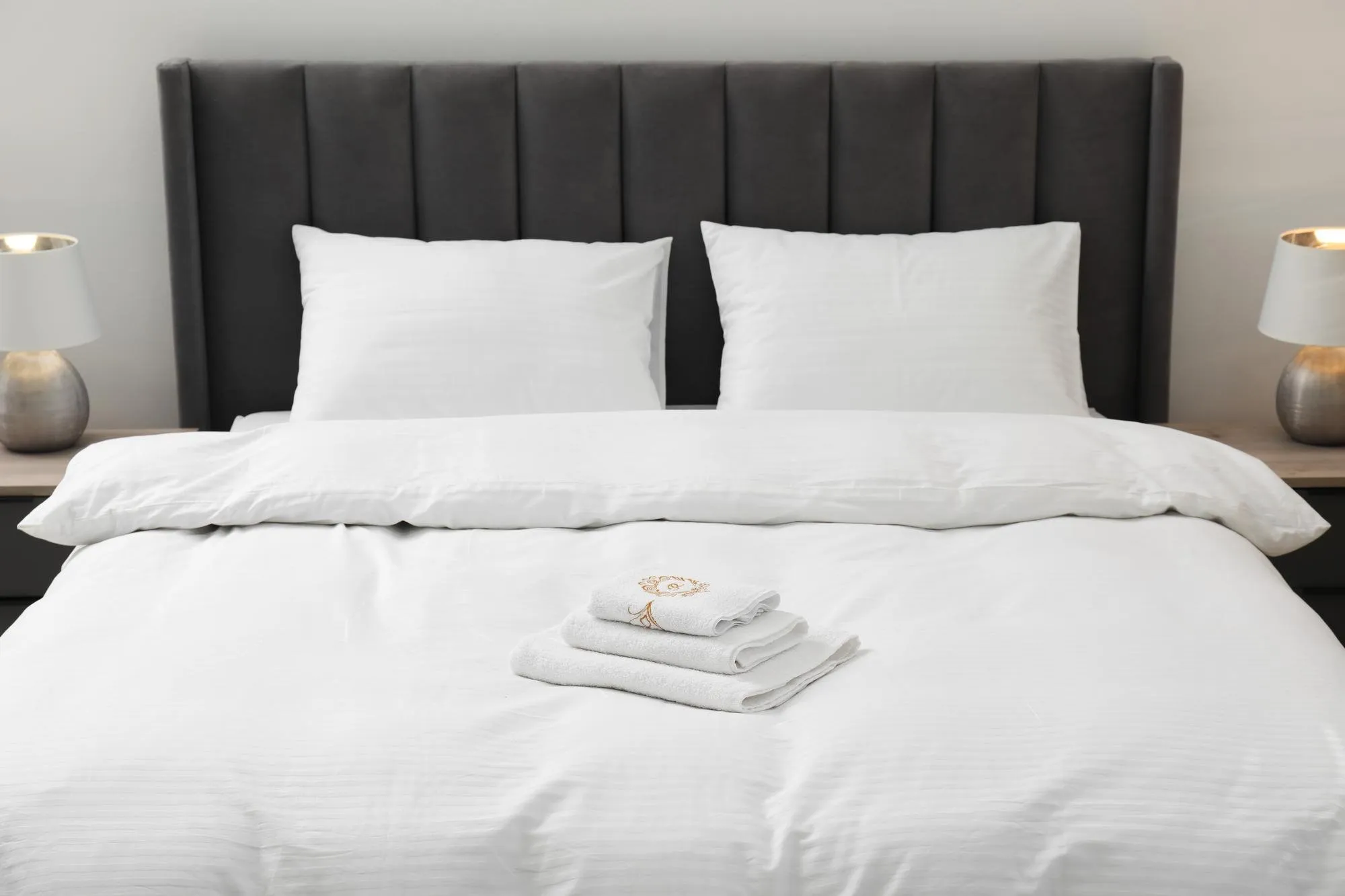 Bed made with fresh white linens and folded towels after a DITA Pro Clean short-term rental turnover in Detroit